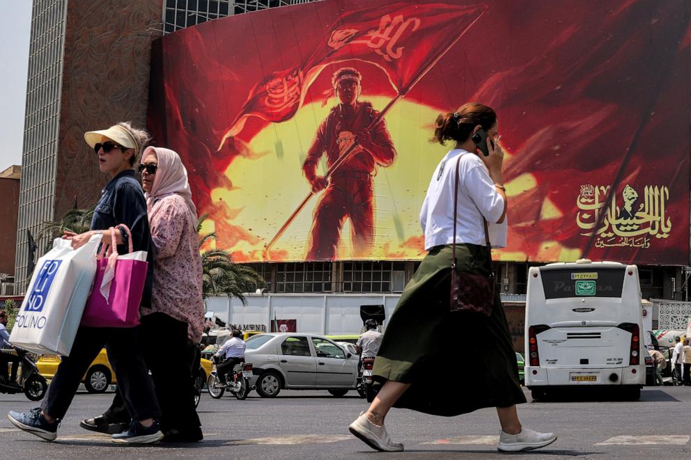 PHOTO: Women walk past a political billboard at Valiasr Square in central Tehran on August 8, 2026.