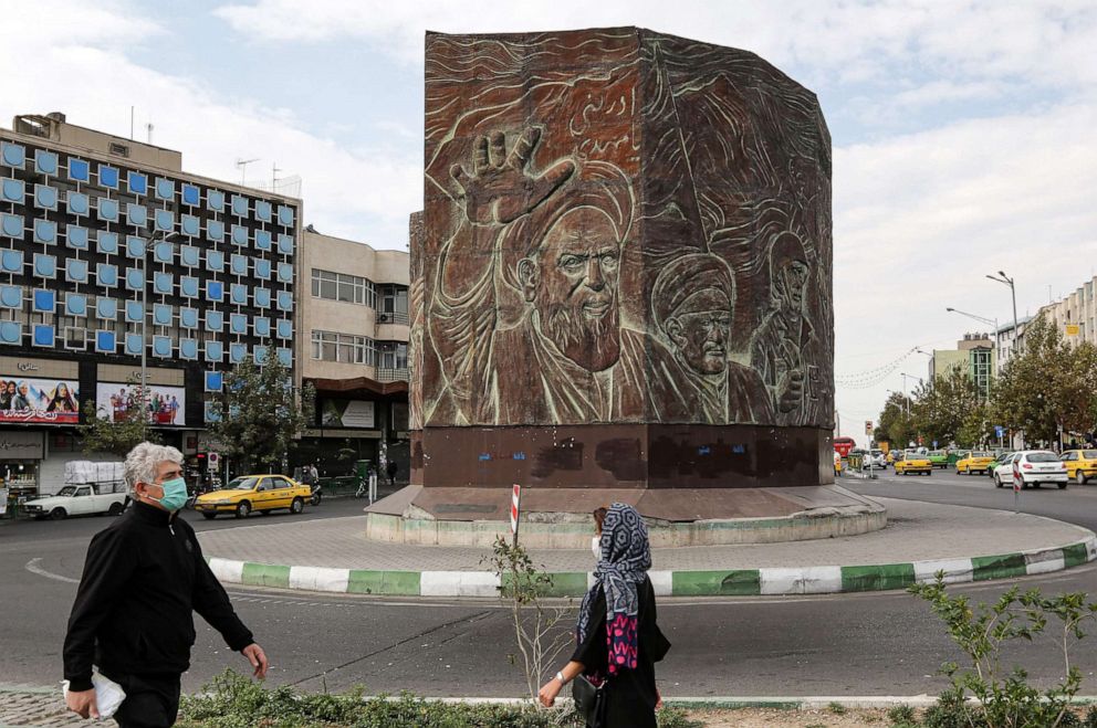 PHOTO: People wearing masks due to the coronavirus pandemic walk near a monument dedicated to Islamic Republic founder Ayatollah Ruhollah Khomeini along Enghelab Square in the center of Iran's capital Tehran, Nov. 8, 2020.