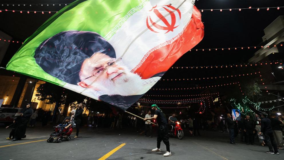 PHOTO: A man waves a flag near Imam Reza's shrine as mourners arrive for the funeral of slain Iranian leader Ali Khamenei and members of his family in Mashhad early on July 9, 2026.
