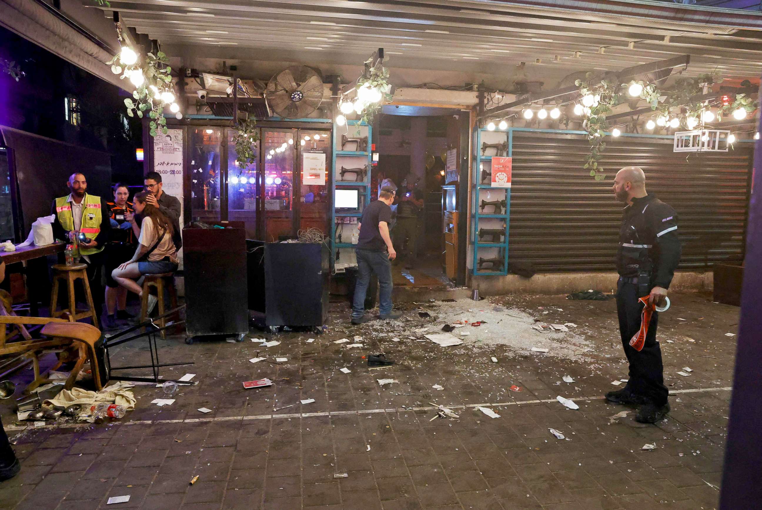 PHOTO: People walk through the scene of a shooting attack at a cafe in Disengoff Street in the center of Tel Aviv, Israel, April 7, 2022.