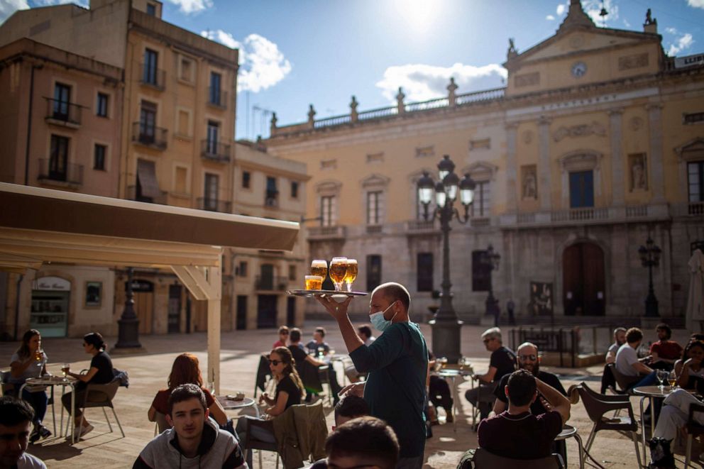 PHOTO: A waiter carries beers for customers sitting at a terrace bar in Tarragona, Spain, on May 11, 2020.