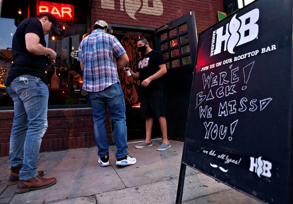 PHOTO: Handlebar bouncer, Mando Cuadros, sprays down a guest's hands with hand sanitizer on the first night that bars reopen after they were shut down to stop the spread of the coronavirus disease (COVID-19) in Austin, Texas, May 22, 2020.