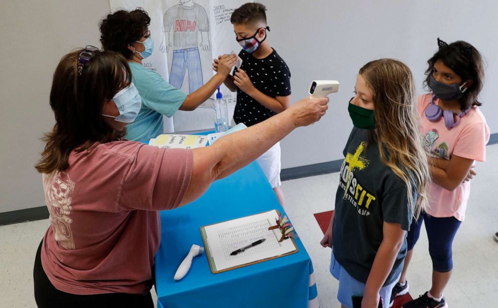 PHOTO: Amid concerns of the spread of COVID-19, science teachers Ann Darby, left, and Rosa Herrera check-in students before a summer STEM camp at Wylie High School in Wylie, Texas, July 14, 2020.