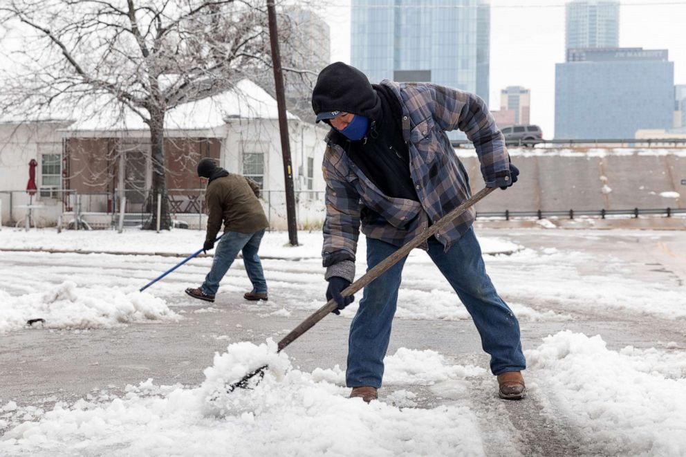 PHOTO: Residents shovel snow from the street in front of a home in East Austin, Texas, Feb. 17, 2021.