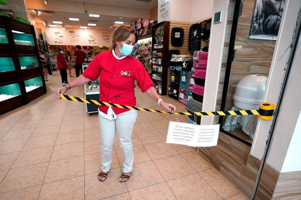 PHOTO: Store manager Natalie Hijazi temporarily closes off the entrance to store inside The Woodlands Mall to help meet occupancy limits, May 5, 2020, in The Woodlands, Texas.