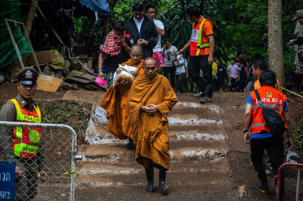 PHOTO: Monks lead out family members of the boys from the cave site after a morning prayer on July 7, 2018 in Chiang Rai, Thailand.