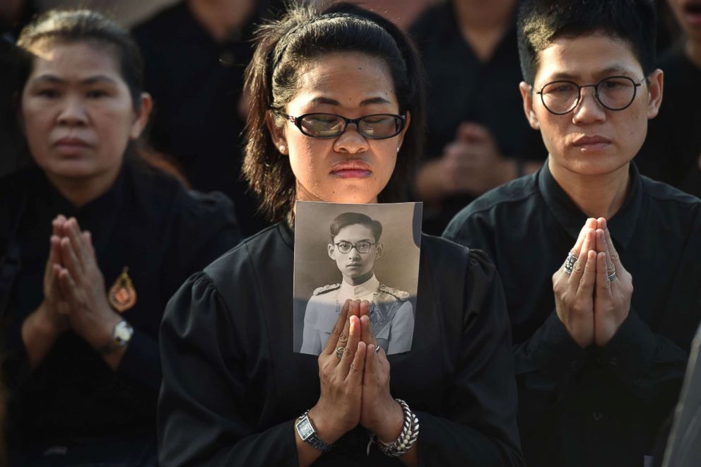 PHOTO: A mourner holds an image of the late Thai King Bhumibol Adulyadej as she waits for his funeral procession to take place in Bangkok, Oct. 26, 2017.