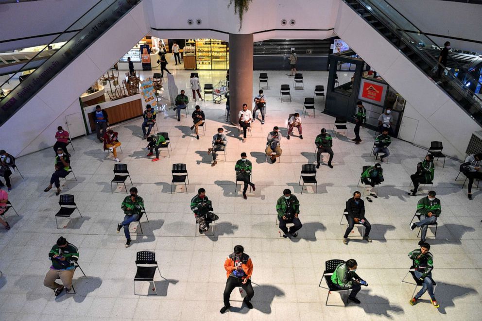 PHOTO: Staff of food delivery companies sit in chairs to maintain social distancing due to the coronavirus (COVID-19) outbreak, as they wait for their customers orders at a department store in Bangkok, Thailand, March 24, 2020. 