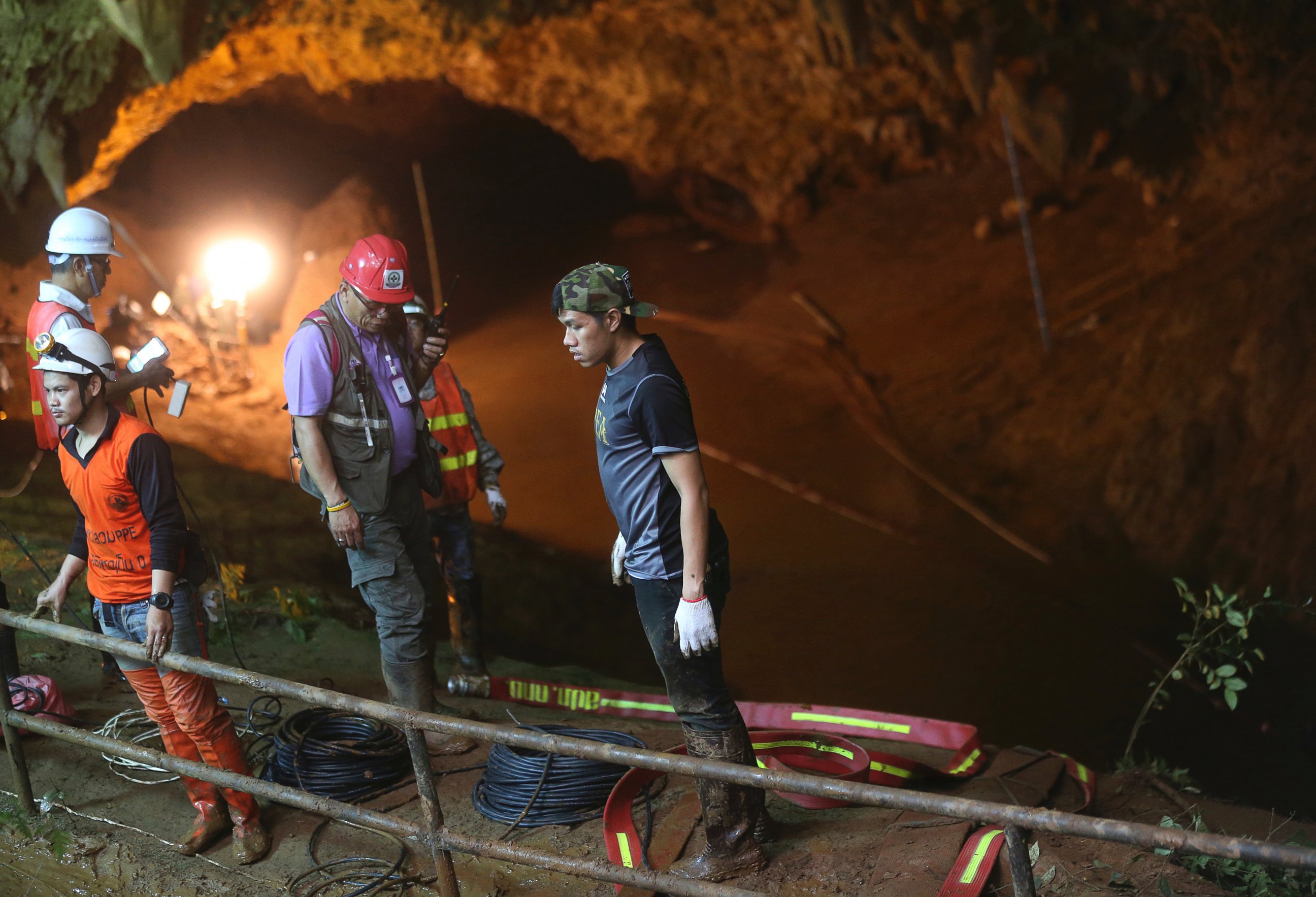 Rescue personnel walk out of the entrance to a cave complex where it's believed that 12 soccer team members and their coach went missing, Thursday, June 28, 2018, in Mae Sai, Chiang Rai province, in northern Thailand.