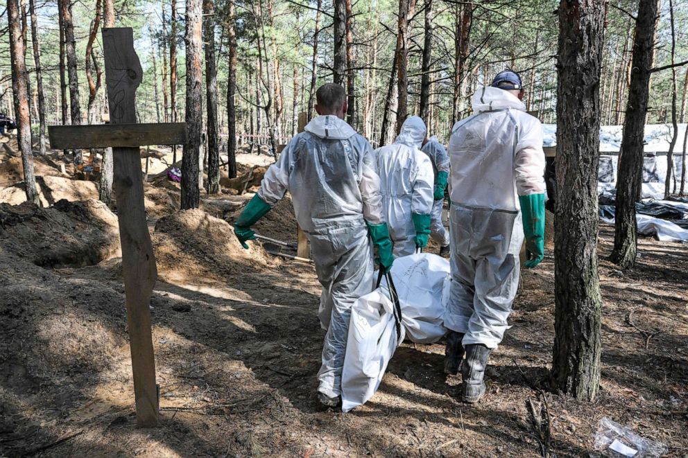 PHOTO: Forensic technicians carry a body in a bodybag at the site of a mass grave in a forest on the outskirts of Izyum, eastern Ukraine, Sept. 18, 2022.