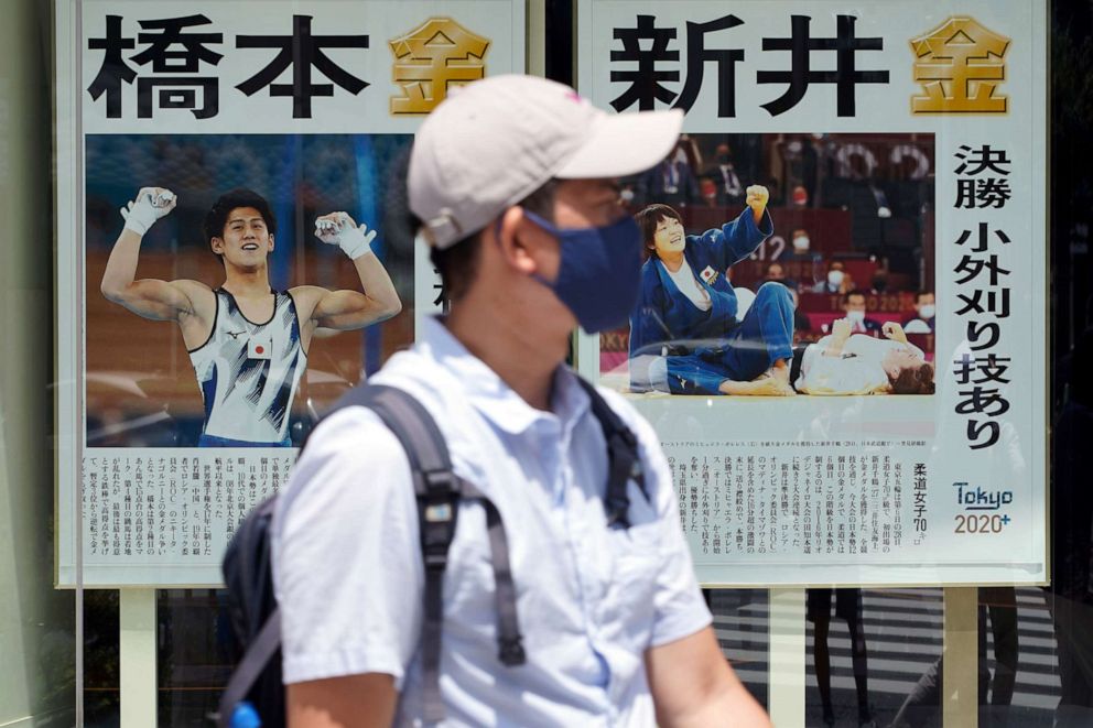 PHOTO: A man walks past papers displaying Japanese gold medalists at the 2020 Summer Olympics, Thursday, July 29, 2021, in Tokyo, Japan.