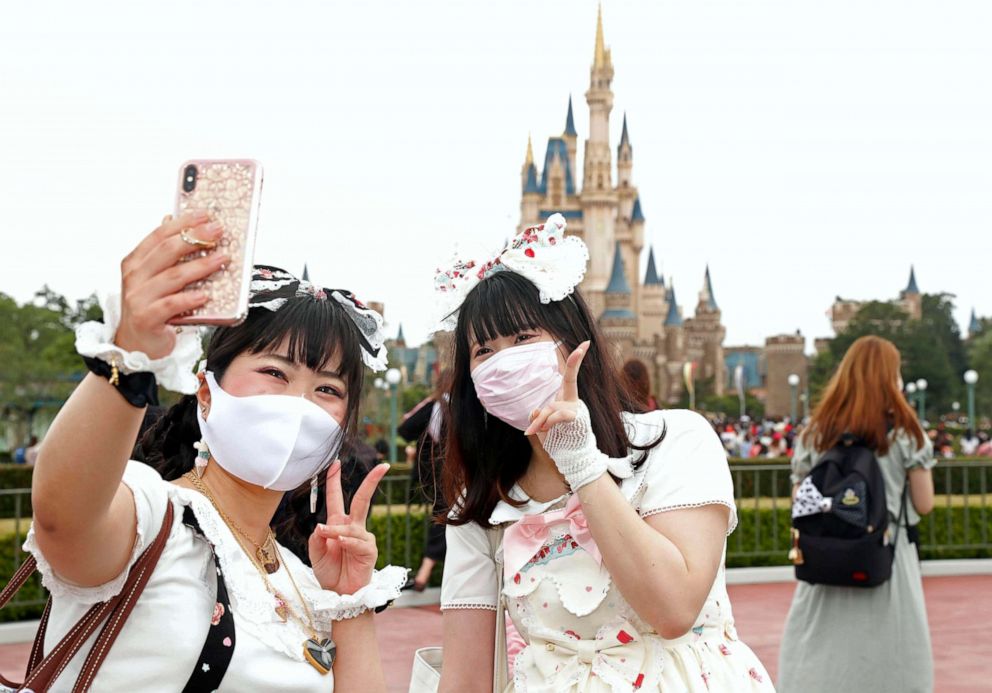 PHOTO: Visitors wearing face masks to protect against the spread of the novel coronavirus take a selfie at Tokyo Disneyland in Urayasu, near Tokyo, Japan, on July 1, 2020.