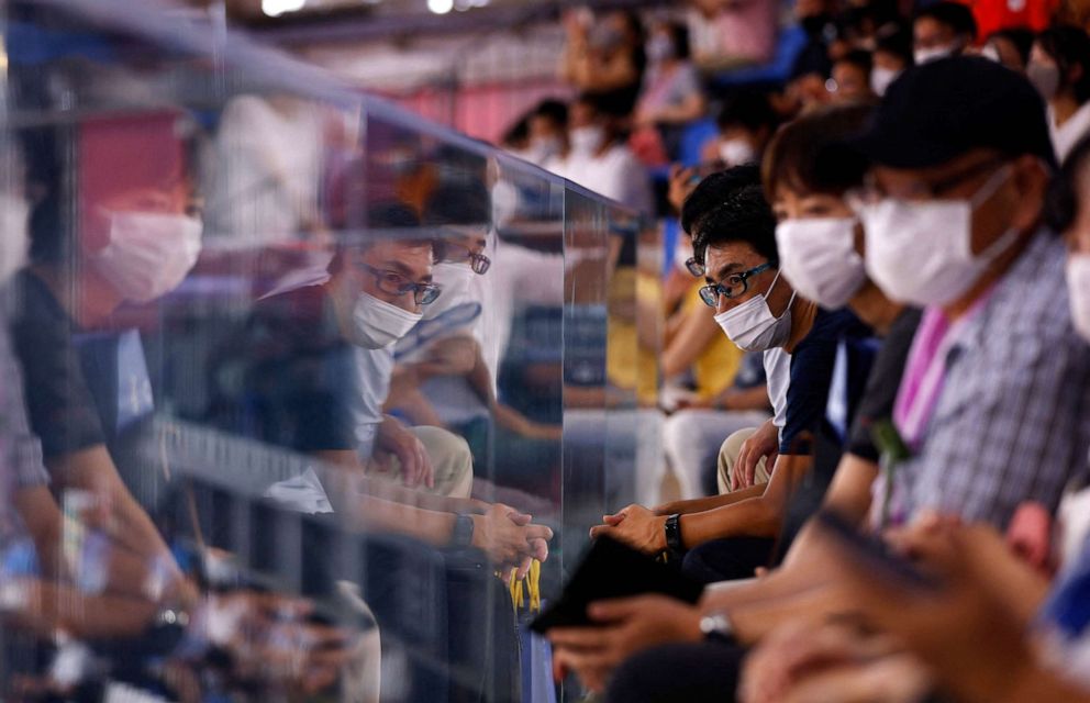 PHOTO: Spectators wearing facemasks are reflected in a barrier as they watch the women's track cycling team pursuit qualifying event during the Tokyo 2020 Olympic Games at Izu Velodrome in Izu, Japan, on Aug. 2, 2021.