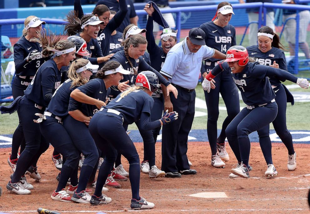 PHOTO: Kelsey Stewart #7 of Team United States jumps on home plate as the umpire and her teammates watch her score the winning run after Stewart hit a walk-off home run in the seventh inning against Team Japan.