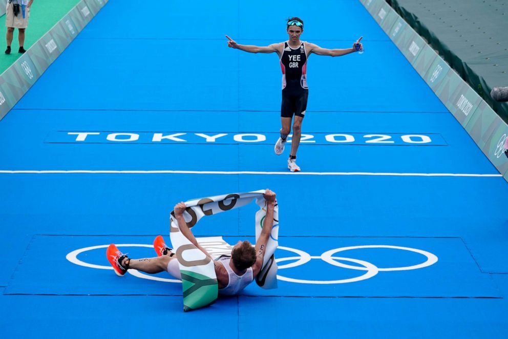 PHOTO: Kristian Blummenfelt of Norway celebrates his gold medal victory as Alex Yee of Great Britain crosses the finish line for the silver medal during the men's individual triathlon at the 2020 Summer Olympics, Monday, July 26, 2021, in Tokyo, Japan.