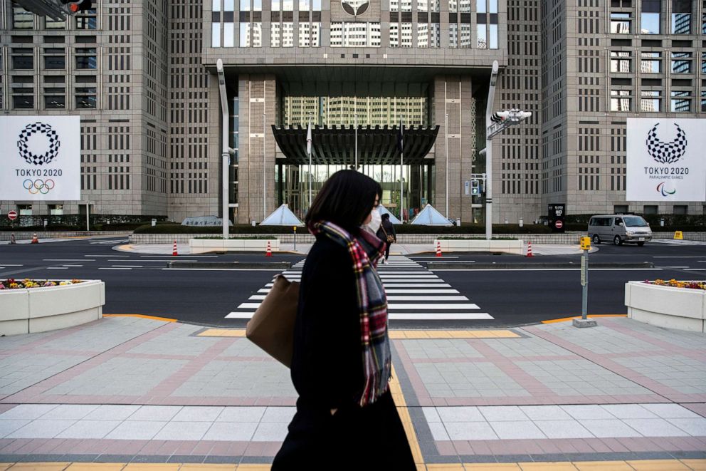 FILE PHOTO: A woman wearing a protective face mask, following an outbreak of the novel coronavirus, walks past banners of the upcoming Tokyo 2020 Summer Olympics outside the Tokyo Metropolitan Government building in Tokyo, Japan, Feb. 28, 2020.