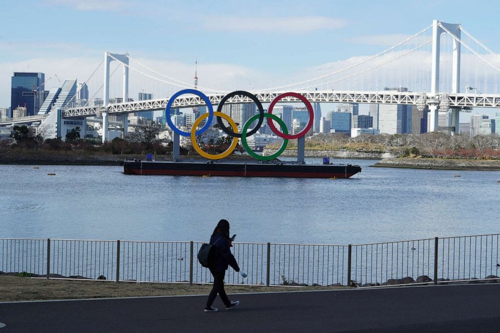 PHOTO: A woman walks near the Olympic rings floating in the water in the Odaiba section of Tokyo, Feb. 18, 2021.