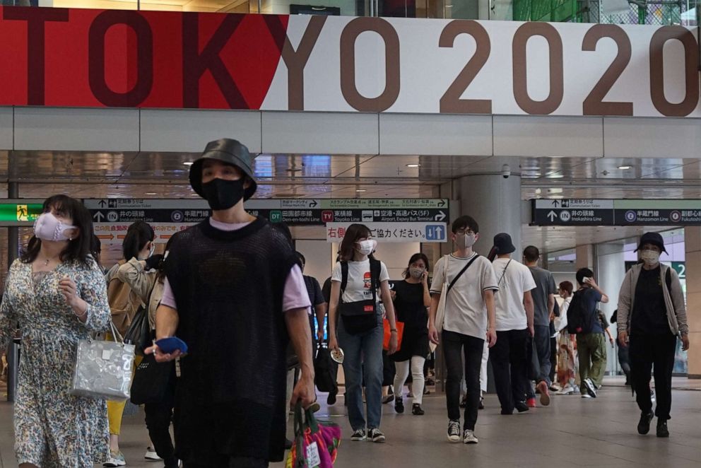 PHOTO: People wearing face masks walk on a concourse at a railway station decorated with a banner for the 2020 Tokyo Olympic and Paralympic Games in Tokyo, Japan, on June 27, 2021.