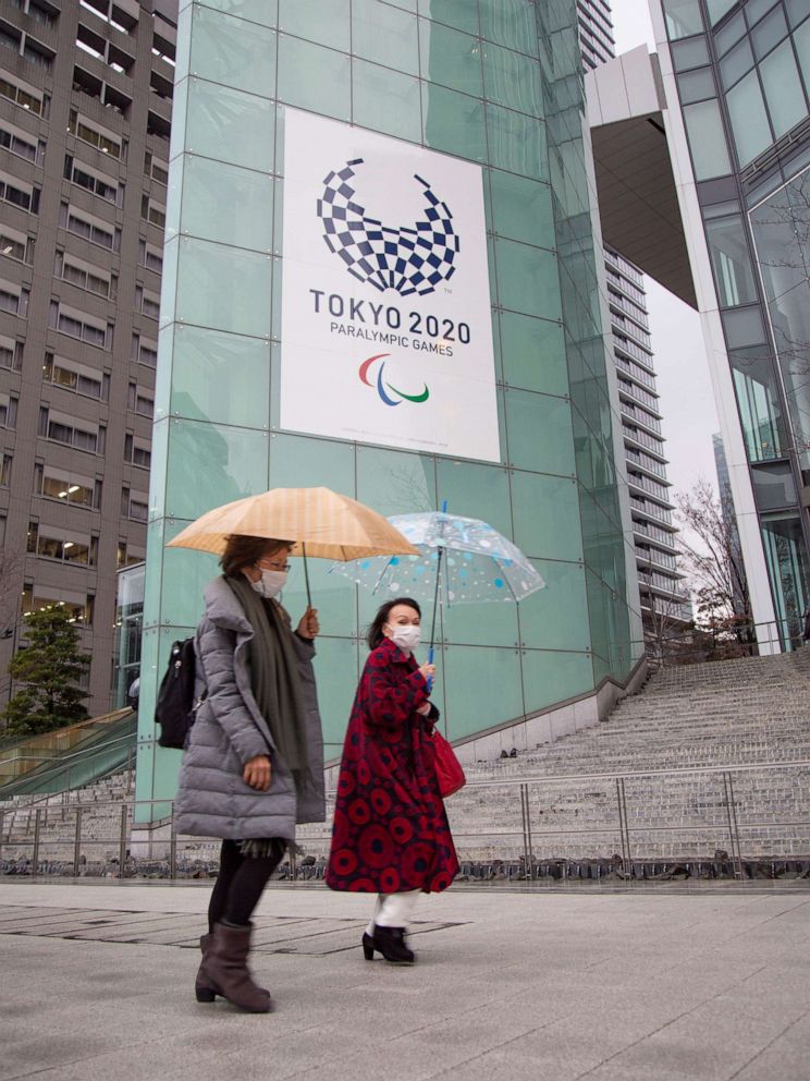 PHOTO: People wearing face masks walk by the headquarters for the Tokyo Organizing Committee of the Olympic and Paralympic Games in Tokyo, Japan, on March 2, 2020.