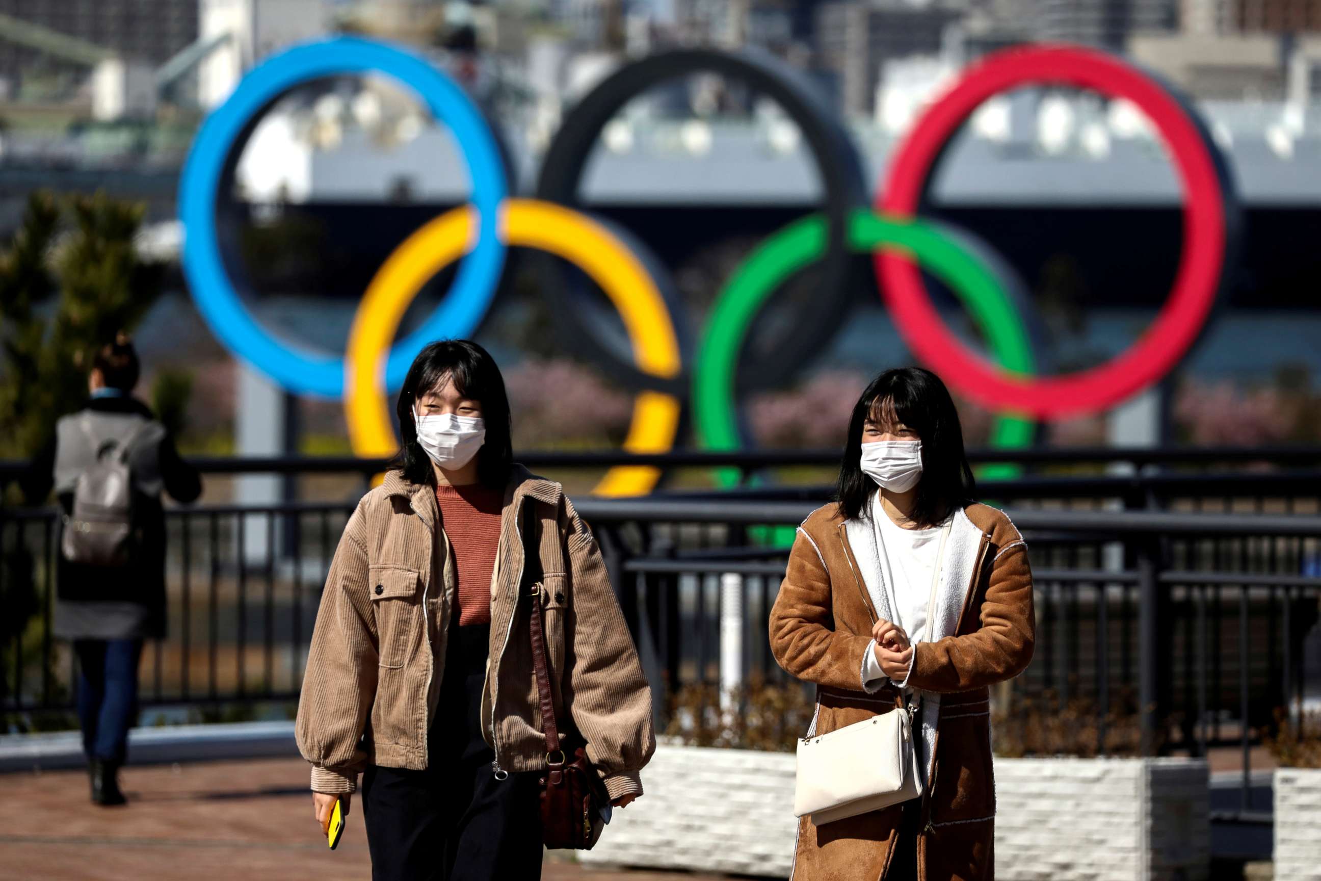 FILE PHOTO: People wearing protective face masks, following an outbreak of the novel coronavirus, are seen in front of the Giant Olympic rings at the waterfront area at Odaiba Marine Park in Tokyo, Japan, Feb. 27, 2020.