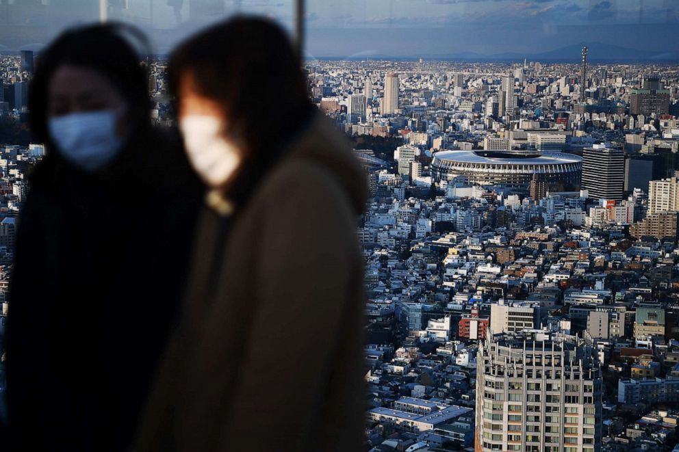 PHOTO: The New Tokyo Stadium, the main venue for the 2020 Summer Olympics, is seen past people wearing face masks at a rooftop viewing area in Tokyo, Japan, on Feb. 8, 2020.