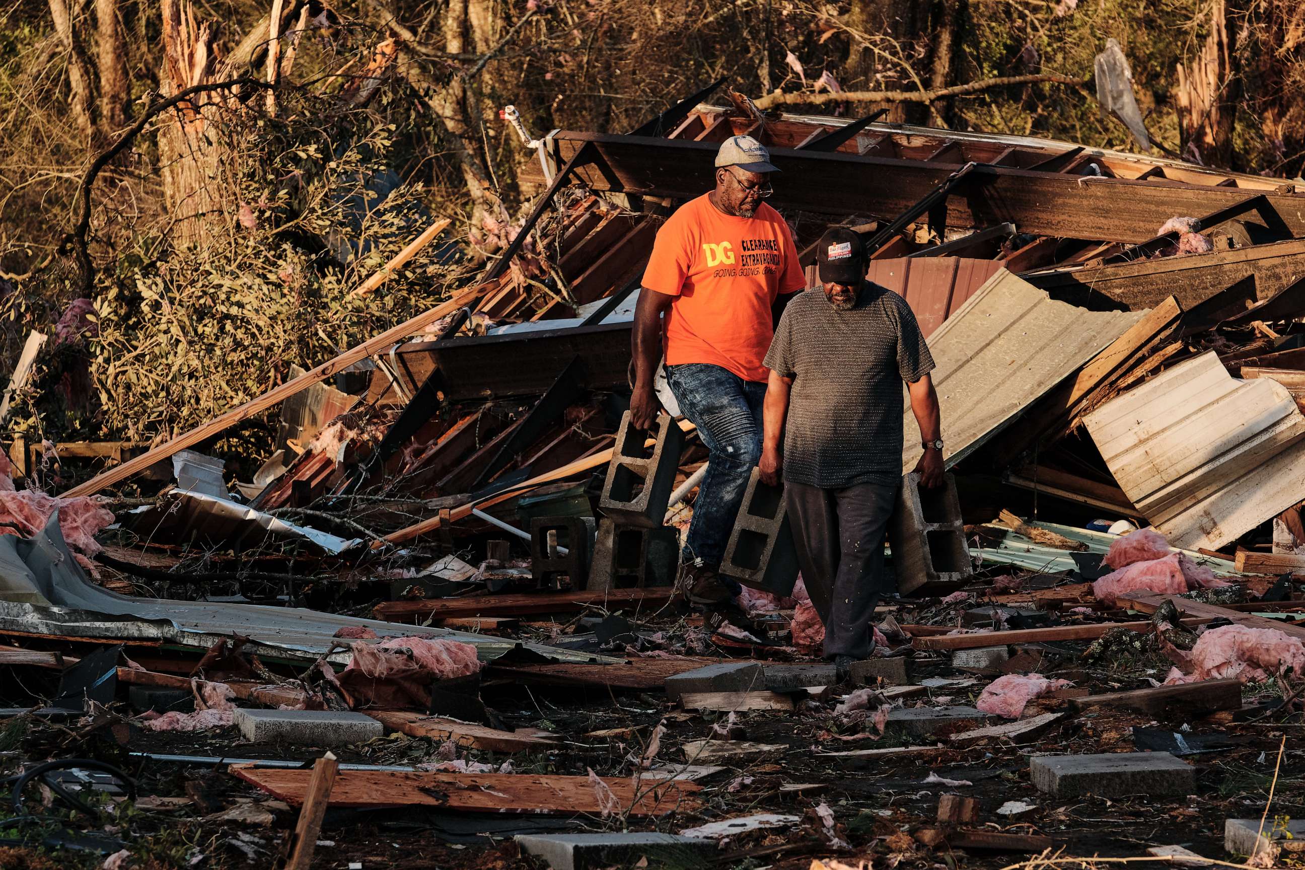 PHOTO: Arthur Threatt, front, and Rob Auxtin try to remove debris on top of a car near trailer homes destroyed by a tornado in Mount Vernon, Alabama, Jan. 12, 2023.