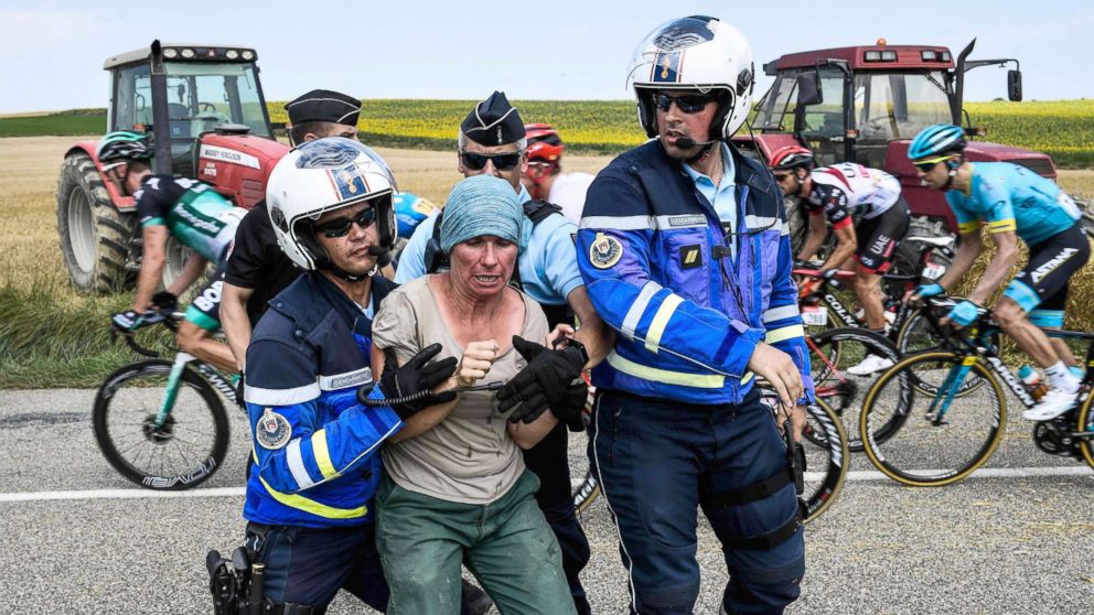 PHOTO: Gendarmes detain a protesting farmer as the pack rides behind during the 16th stage of the 105th edition of the Tour de France cycling race, between Carcassonne and Bagneres-de-Luchon, southwestern France, on July 24, 2018.