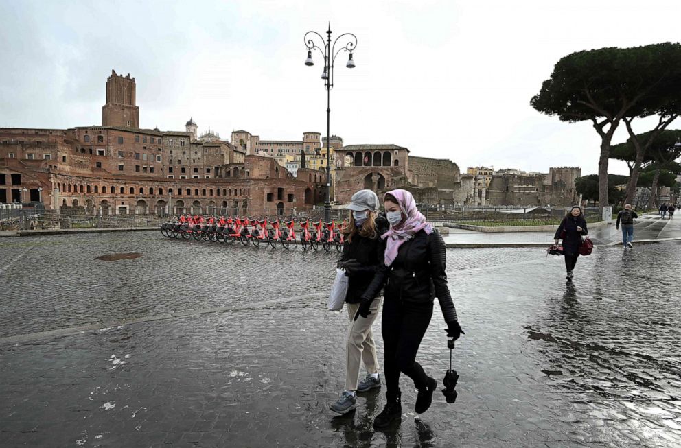 PHOTO: Two women wearing protective masks walks past the Trajan Forum in Rome, Italy, on March 3, 2020.