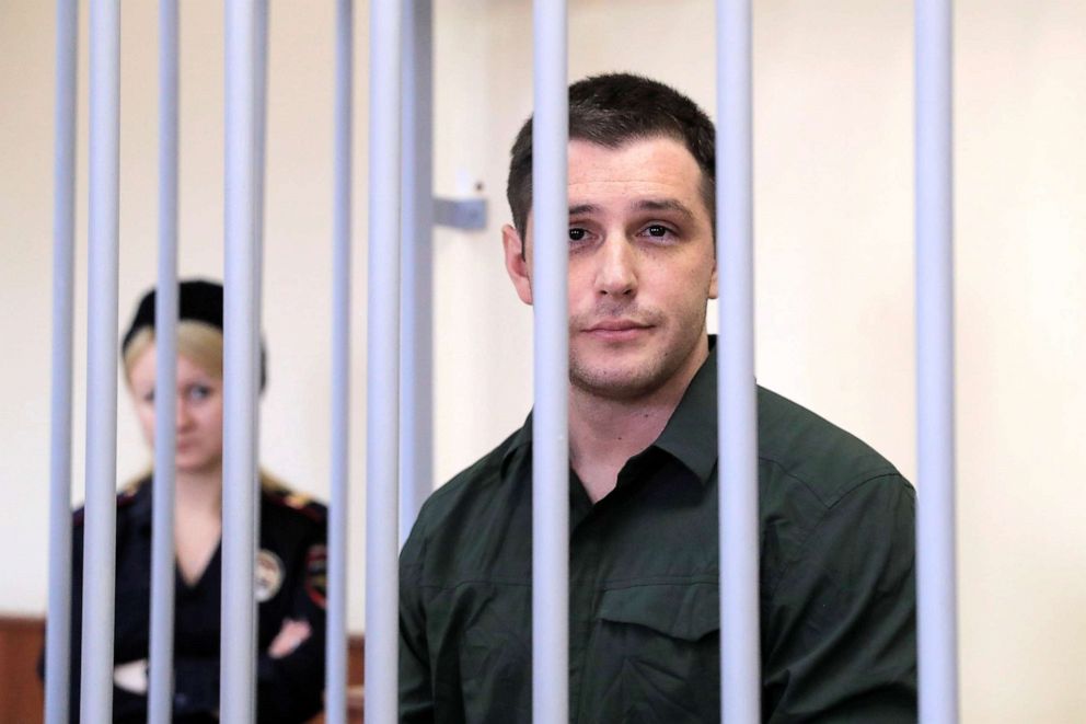 PHOTO: In this March 11, 2020, file photo, U.S. ex-Marine Trevor Reed, who was detained in 2019 and accused of assaulting police officers, stands inside a defendants' cage during a court hearing in Moscow.