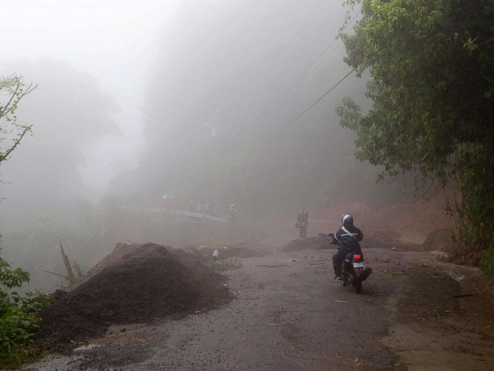PHOTO: Neighbors walk under the rain past a washed out road in Alajuelita on the outskirts of San Jose, Costa Rica, Oct. 5, 2017.