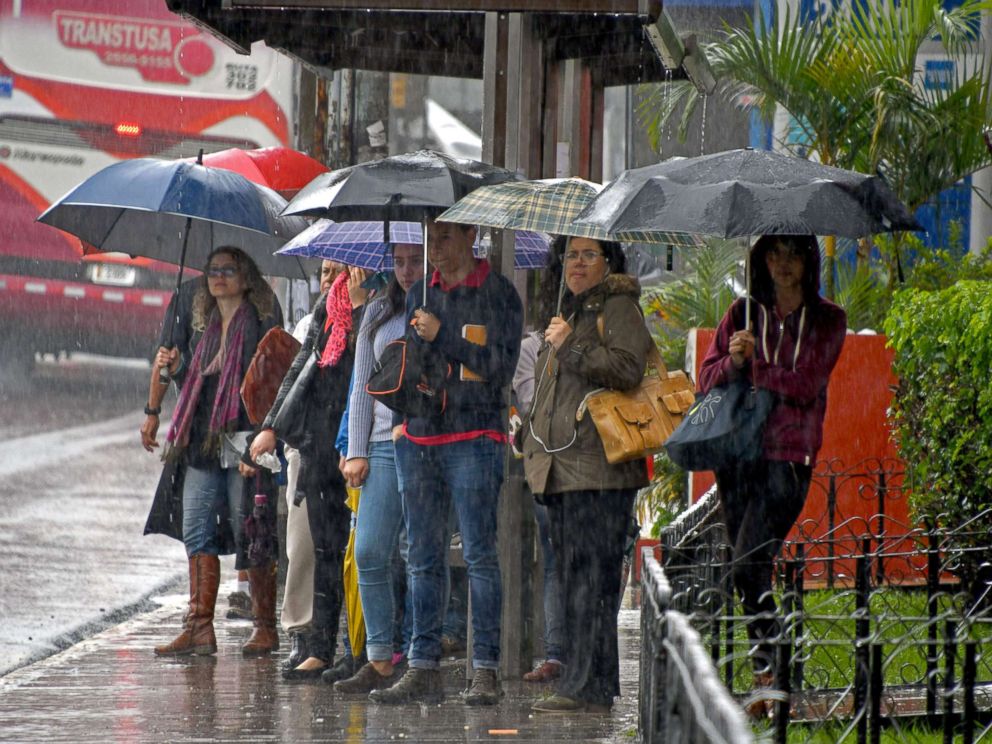PHOTO: Locals holding umbrellas wait at a bus stop during a downpour caused by tropical storm Nate in Cartago, Costa Rica, Oct. 5, 2017.