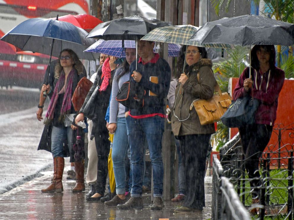 PHOTO: Locals holding umbrellas wait at a bus stop during a downpour caused by tropical storm Nate in Cartago, Costa Rica, Oct. 5, 2017.