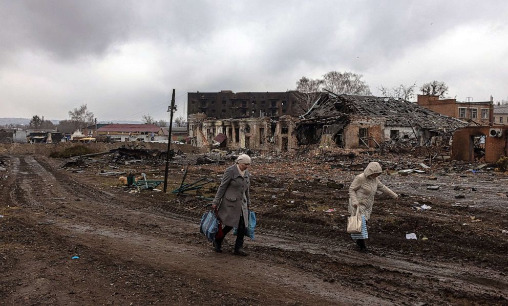 PHOTO: Local residents walk past destroyed buildings and Russian military vehicles, after the town was recaptured by the Ukrainian army, in Trostyanets town, in Sumy region, Ukraine, March 30, 2022.