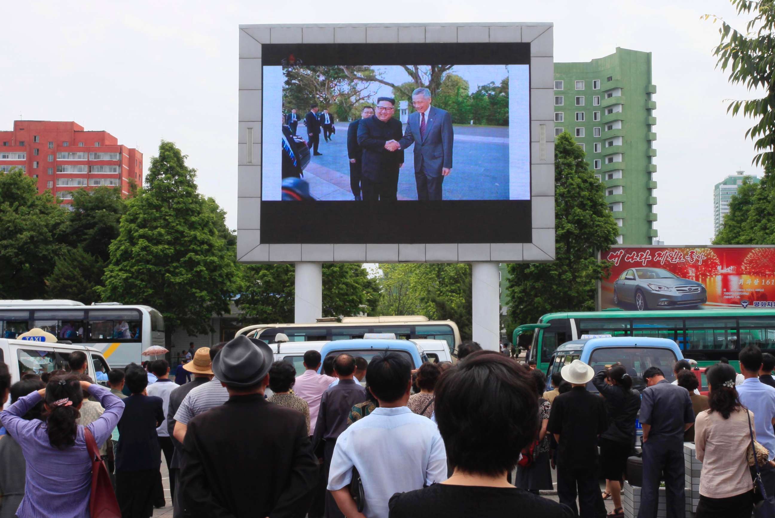 PHOTO: People watch a large screen at the main train station airing video of North Korean leader Kim Jong Un shaking hands with Singapore Prime Minister Lee Hsien Loong during his trip to Singapore in Pyongyang, North Korea, June 11, 2018.
