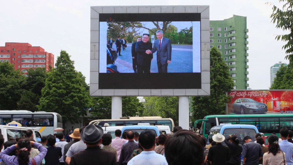 People watch a large screen at the main train station airing video of North Korean leader Kim Jong Un shaking hands with Singapore Prime Minister Lee Hsien Loong during his trip to Singapore in Pyongyang, North Korea, June 11, 2018.