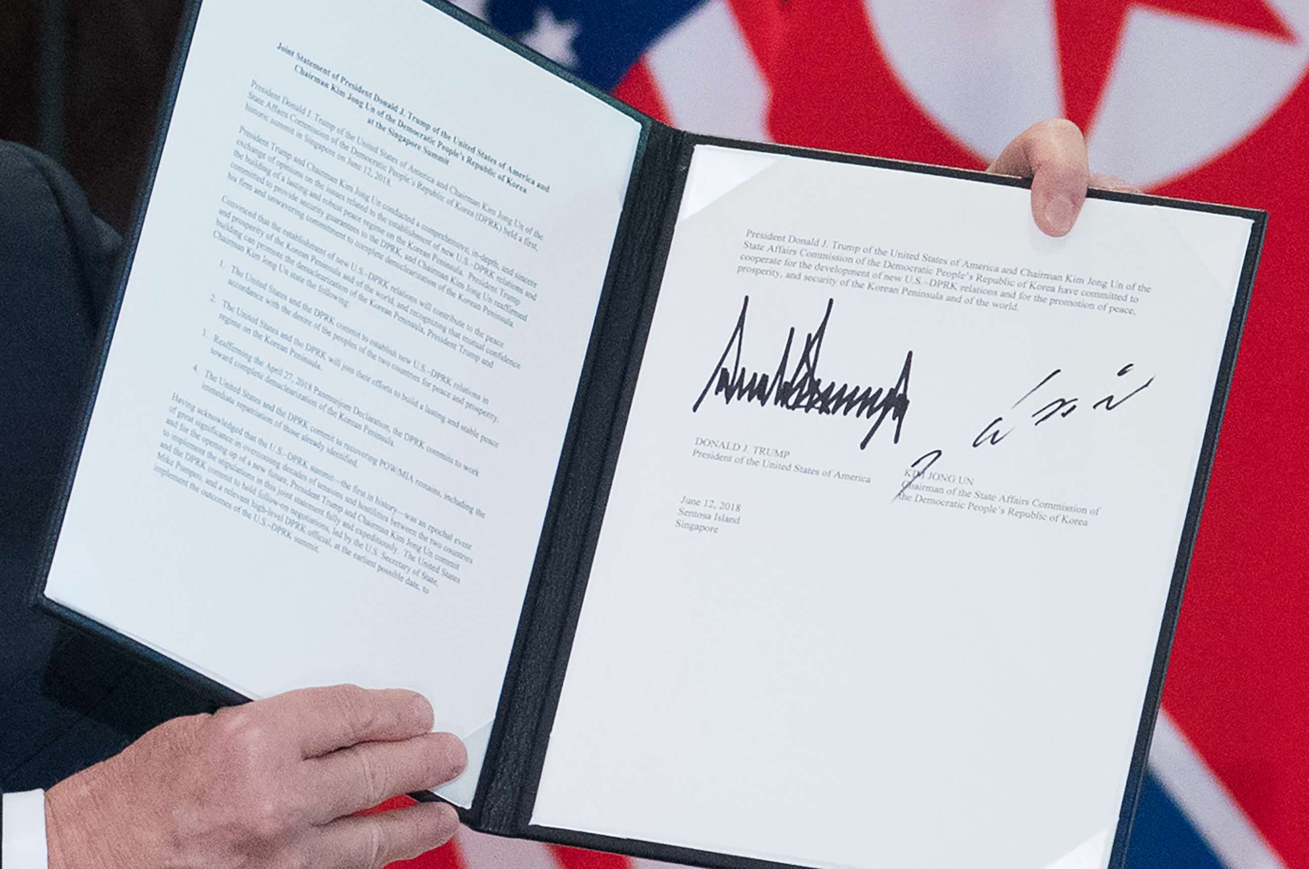 PHOTO: President Donald Trump holds up a document signed by him and North Korea's leader Kim Jong Un following a signing ceremony at the Capella Hotel on Sentosa island in Singapore on June 12, 2018.