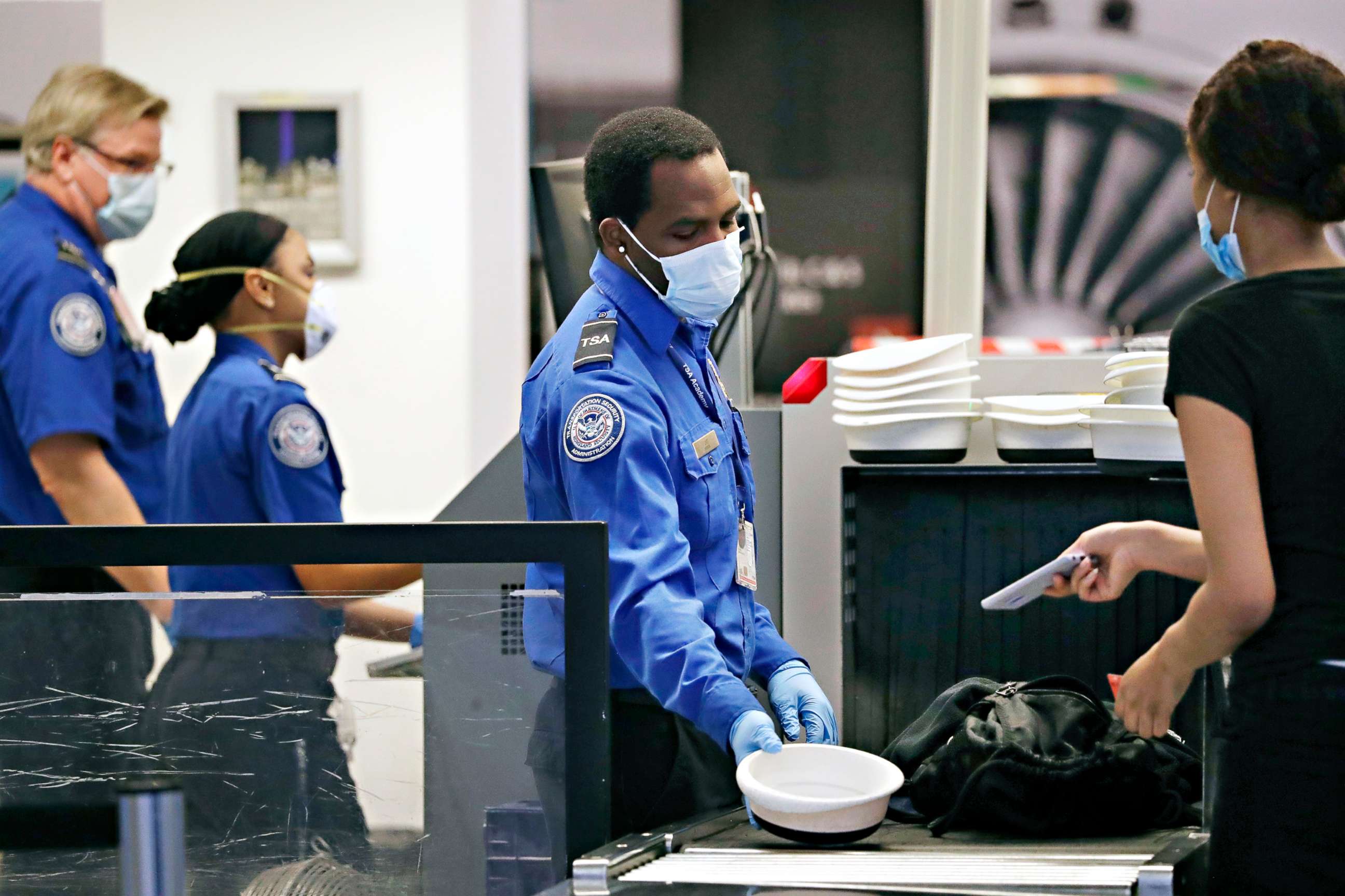 PHOTO: TSA officers wear protective masks at a security screening area at Seattle-Tacoma International Airport, May 18, 2020, in SeaTac, Wash. Travelers at the airport were required to wear face coverings in the public areas starting May 18.