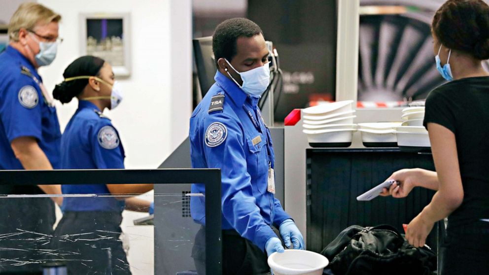 PHOTO: TSA officers wear protective masks at a security screening area at Seattle-Tacoma International Airport, May 18, 2020, in SeaTac, Wash. Travelers at the airport were required to wear face coverings in the public areas starting May 18.