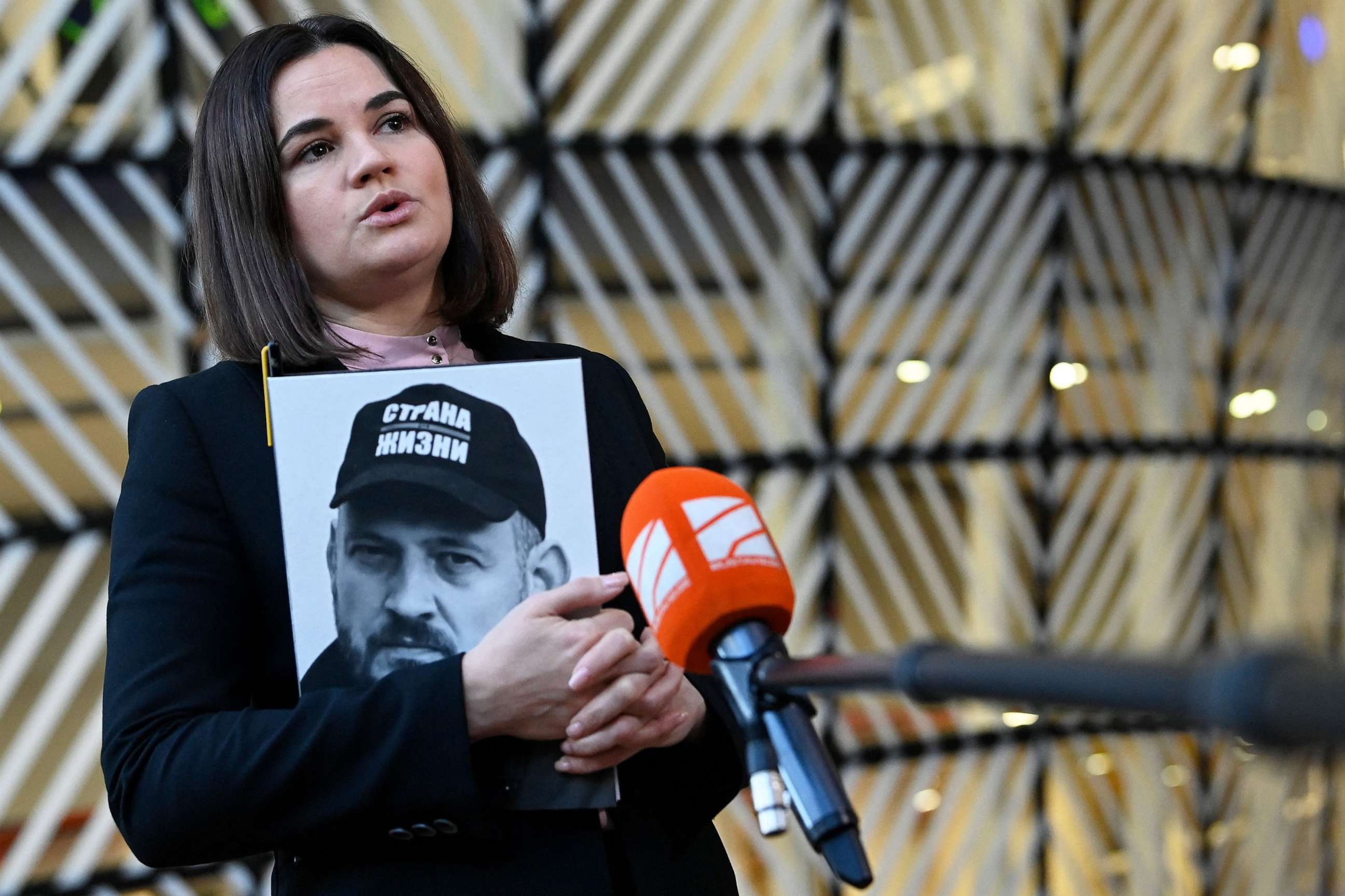 PHOTO: Leader of the Belarusian democratic movement Sviatlana Tsikhanouskaya speaks to the press while holding a portait of her imprisoned husband Sergei Tsikhanousky, in Brussels on Nov. 14, 2022.