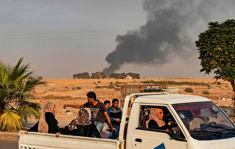 PHOTO: Civilians ride a pickup truck as smoke billows following Turkish bombardment in the northeastern town of Ras al-Ain in Syria's Hasakeh province along the Turkish border on Oct. 9, 2019.