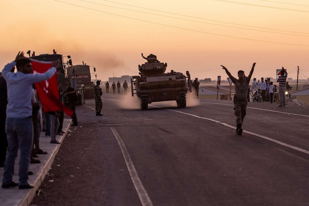 PHOTO: People wave as Turkish soldiers prepare to cross the border into Syria on Oct. 9, 2019, in Akcakale, Turkey. 