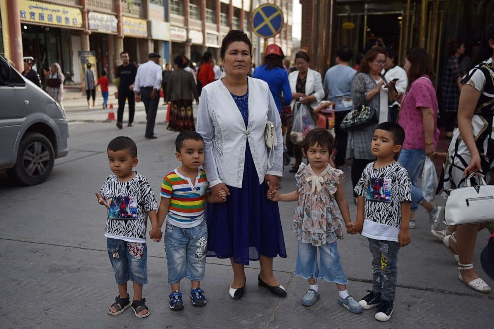 PHOTO: This file photo taken on June 4, 2019, shows a Uighur woman waiting with children on a street in Kashgar in China's northwest Xinjiang region.
