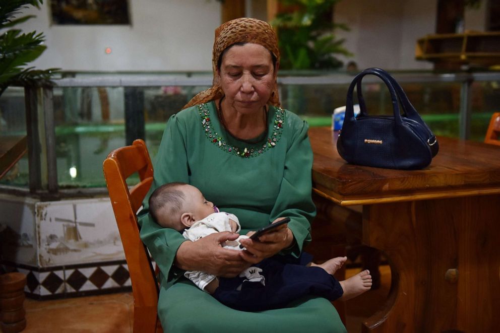 PHOTO: This file photo taken on May 31, 2019, shows a Uighur woman holding a baby in a Uighur restaurant in Hotan in China's northwest Xinjiang region.