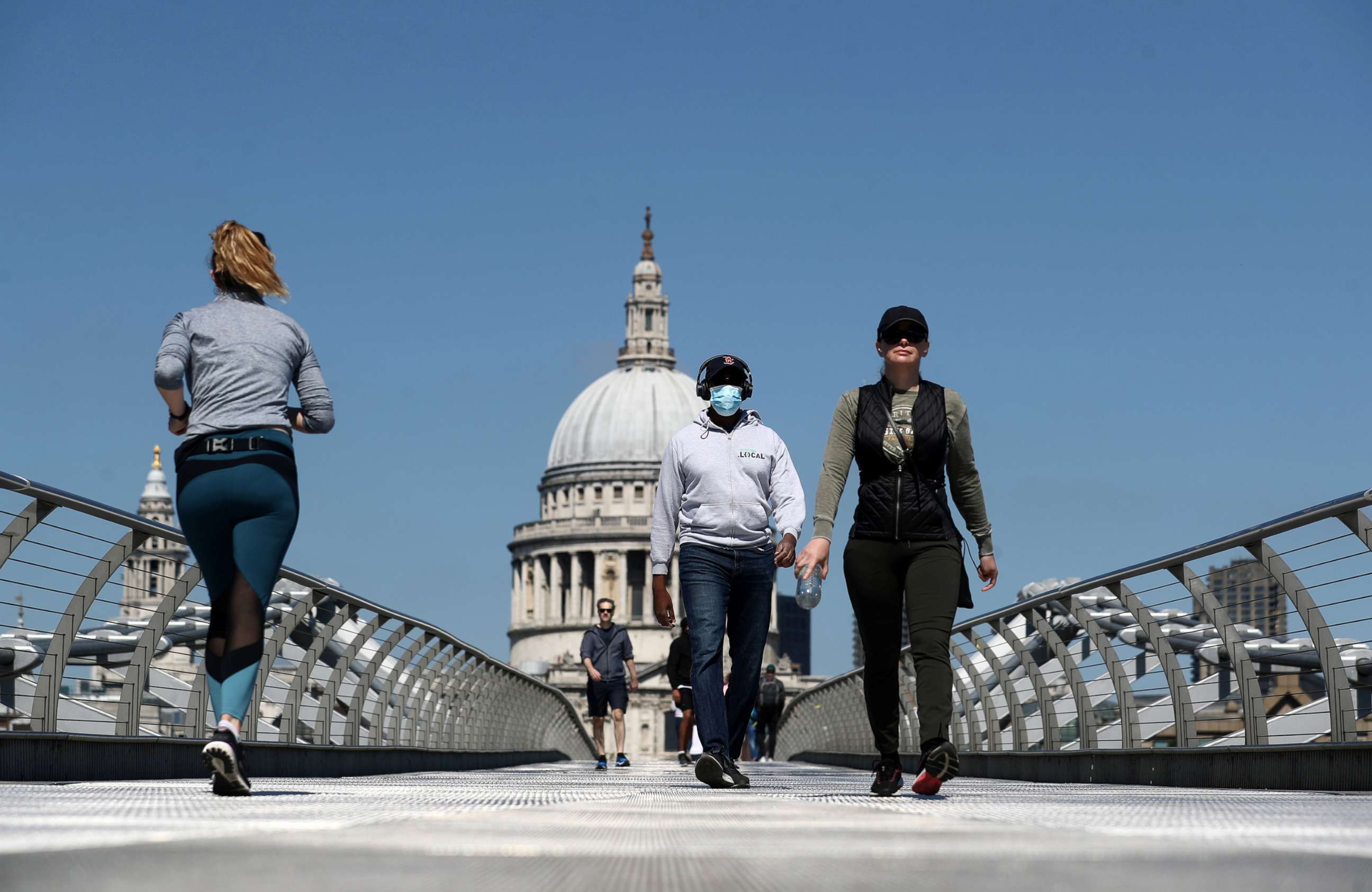 PHOTO: A man wearing a face mask crosses Millennium Bridge, as the spread of the coronavirus disease (COVID-19) continues, in London, Britain, April 25, 2020.