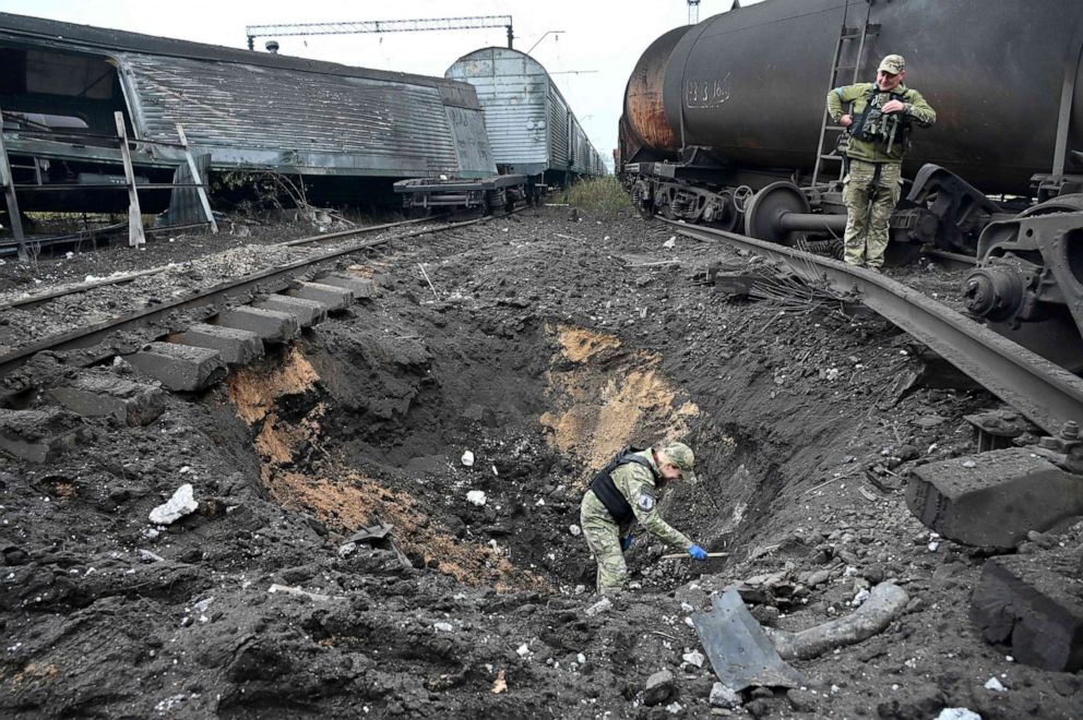 FOTOĞRAF: Adli bir patlayıcı uzmanı, Rusya'nın Ukrayna'yı işgali sırasında 21 Eylül 2022'de Kharkiv'deki bir yük tren istasyonundaki füze patlamasından kaynaklanan bir krateri inceliyor. 