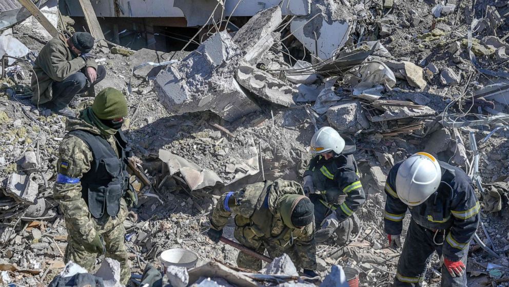 PHOTO: Ukrainian soldiers and rescue officers search for bodies in the debris at the military school hit by Russian rockets the day before, in Mykolaiv, southern Ukraine, March 19, 2022.