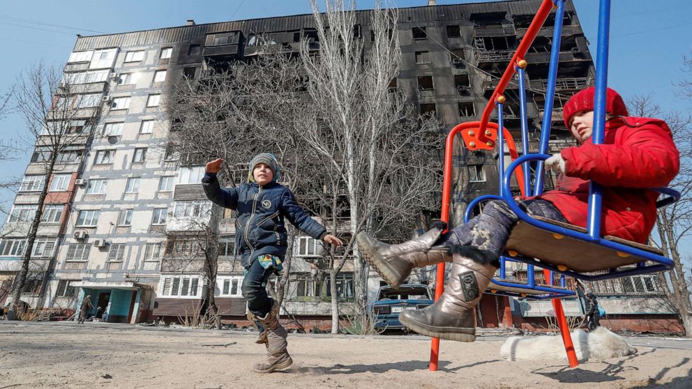 PHOTO: Children play in front of a building damaged in fighting during the Russian invasion of Ukraine, in the besieged southern port of Mariupol, Ukraine, March 23, 2022.  