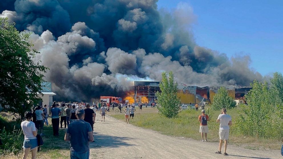 PHOTO: People watch as smoke bellows after a Russian missile strike hit a crowded shopping mall, in Kremenchuk, Ukraine, June 27, 2022.