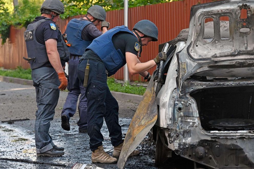 PHOTO: Deminers examine the site of a reported cluster munition fall next to a burnt car after a rocket attack on a residential area in northern Kharkiv, Aug. 8, 2022, amid the Russian military invasion of Ukraine.