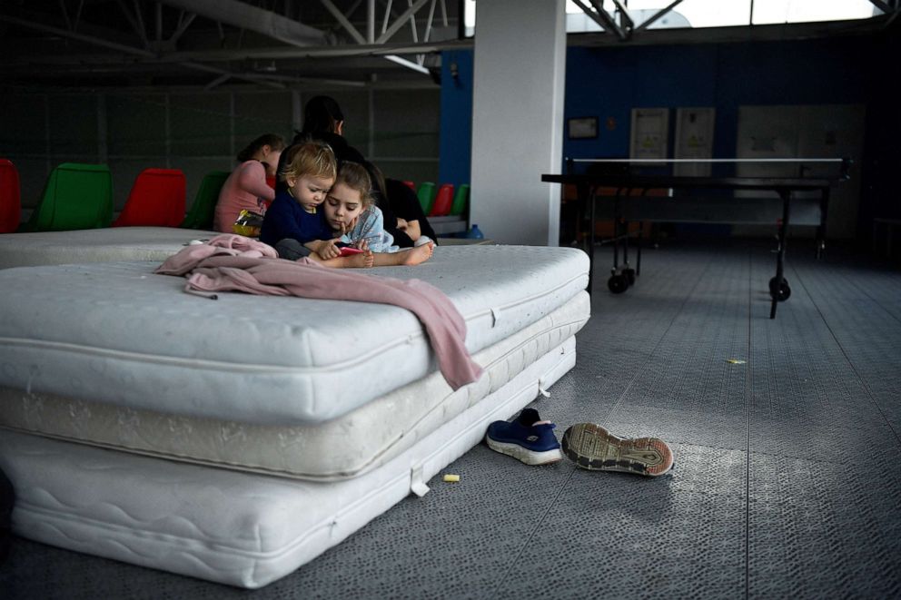 PHOTO: Raquela, 2, and Manuela watch cartoons on an iPhone at Dumbraveni sports arena which has been converted to a temporary shelter, after they fled with their families from the beseiged Ukraine in Suceava, Romania March 15, 2022.